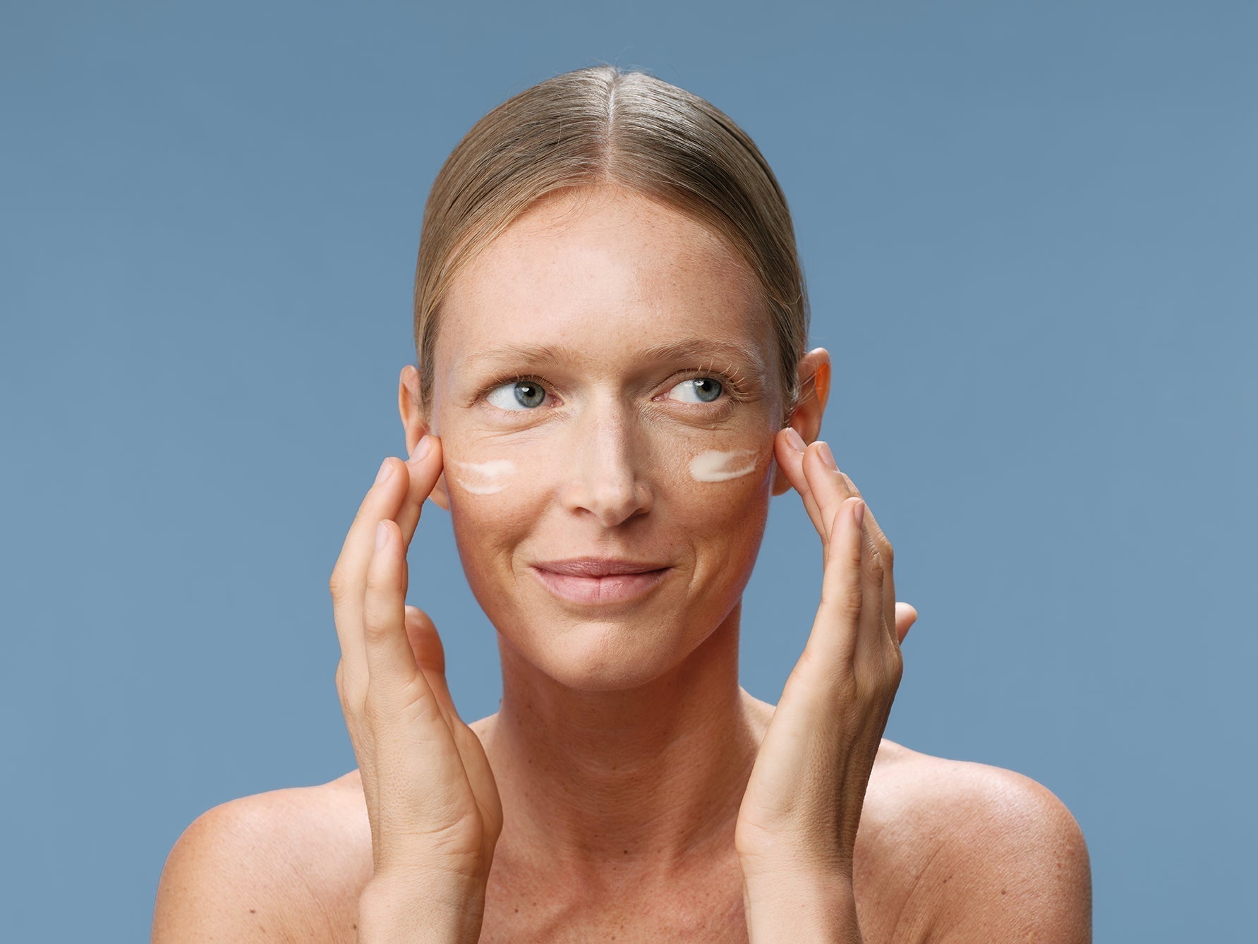 woman applying cream on her face